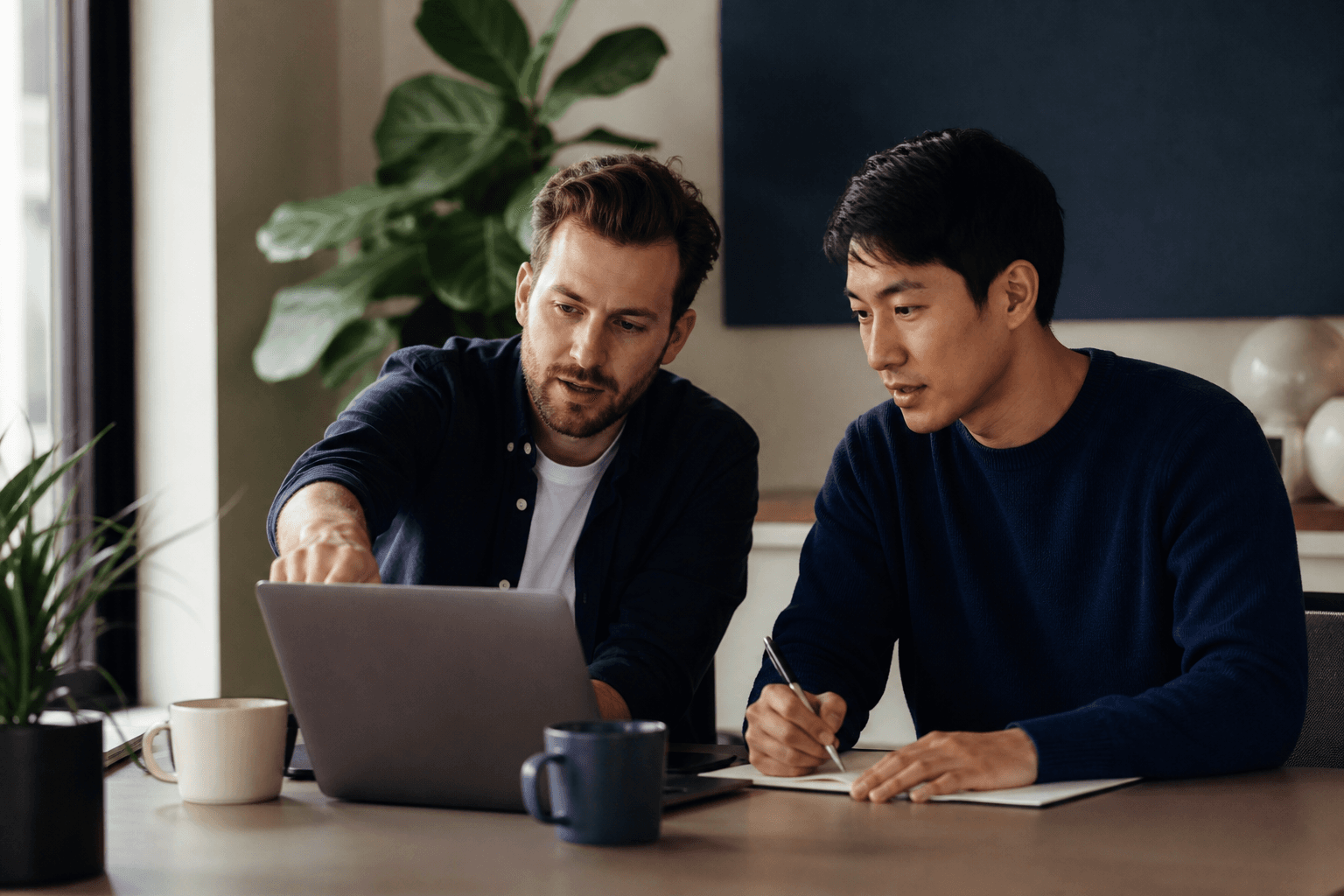 Two engineers pair-programming at a sunlit desk